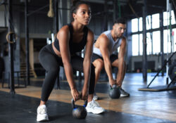 Fit and muscular couple focused on lifting a dumbbell during an exercise class in a gym.